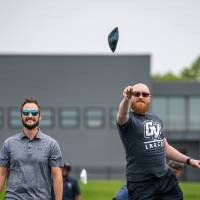 Man underhand tossing a cornhole bag into the air